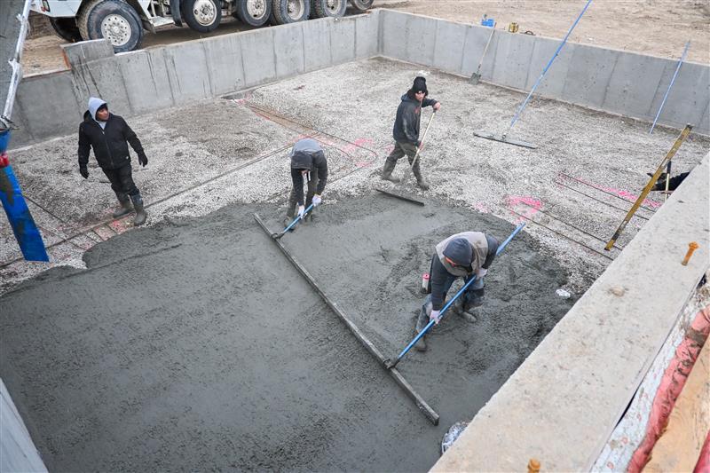 Crew placing and leveling commercial concrete slab during construction